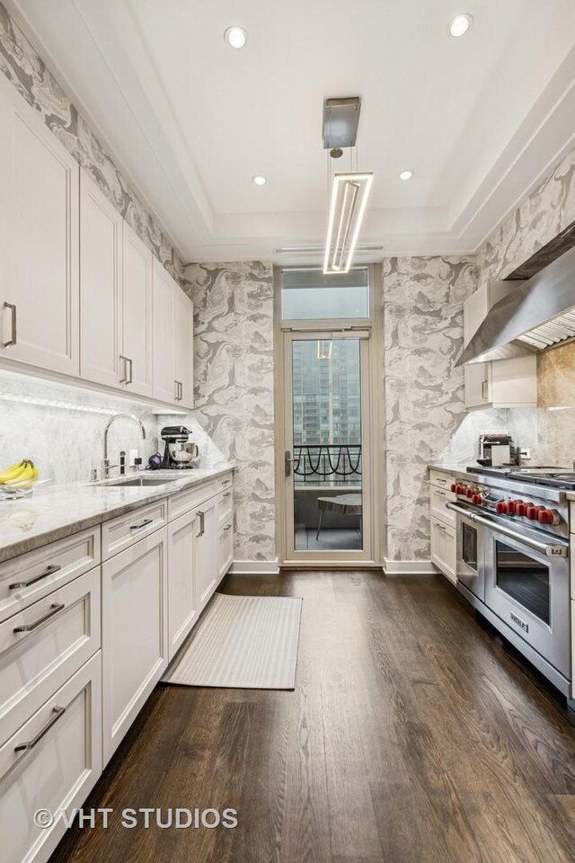 118 E Erie St Unit 21D, Chicago, IL 60611 - kitchen featuring double oven range, a sink, dark wood finished floors, white cabinets, and light stone counters