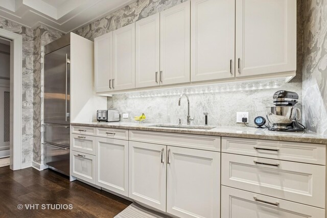 118 E Erie St Unit 21D, Chicago, IL 60611 - kitchen featuring a sink, wallpapered walls, dark wood finished floors, white cabinetry, and light stone countertops
