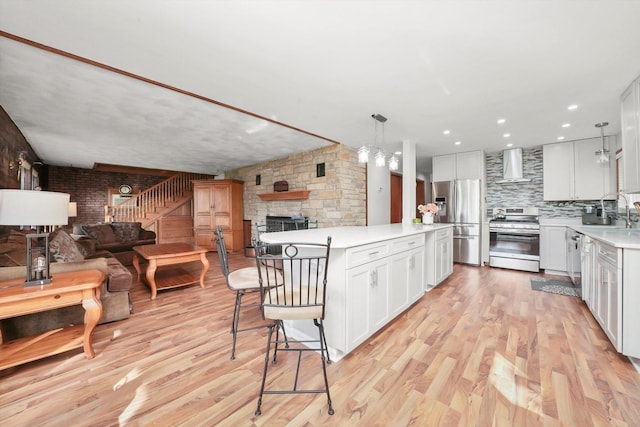 1423 N River Rd, Mchenry, IL 60050 - kitchen featuring appliances with stainless steel finishes, wall chimney exhaust hood, open floor plan, a fireplace, and light countertops