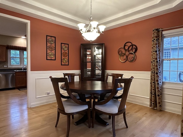 445 Spring Park Loop, Bourbonnais, IL 60914 - dining room featuring a raised ceiling, light wood-style floors, a chandelier, wainscoting, and a decorative wall