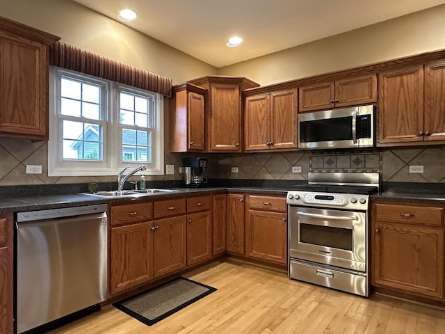 445 Spring Park Loop, Bourbonnais, IL 60914 - kitchen featuring appliances with stainless steel finishes, a sink, light wood-type flooring, dark countertops, and brown cabinets