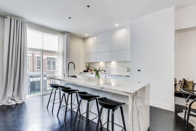 335 E Cullerton St, Chicago, IL 60616 - kitchen featuring modern cabinets, white cabinetry, decorative backsplash, a kitchen breakfast bar, and a sink
