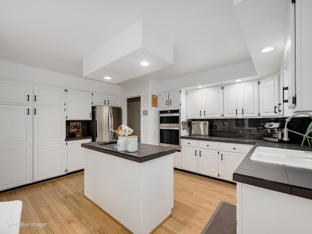 411 Linden Ave, Oak Park, IL 60302 - kitchen with appliances with stainless steel finishes, dark countertops, a sink, white cabinetry, and recessed lighting