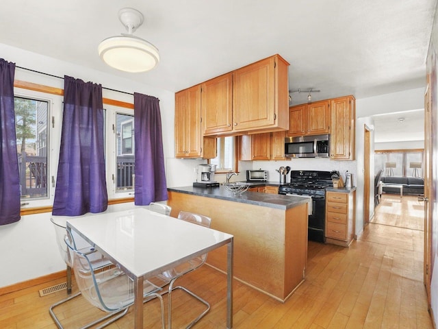 3405 N Osage Ave, Chicago, IL 60634 - kitchen with stainless steel microwave, black gas stove, a sink, light wood finished floors, and dark countertops