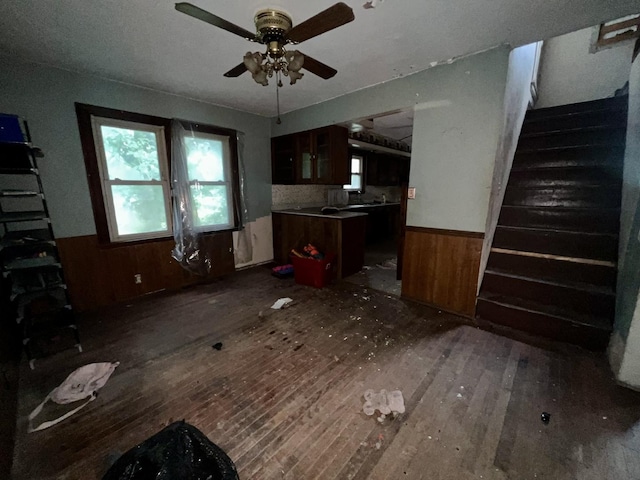 103 W 2nd St, Broadlands, IL 61816 - unfurnished living room featuring wood-type flooring, a wainscoted wall, wooden walls, and ceiling fan