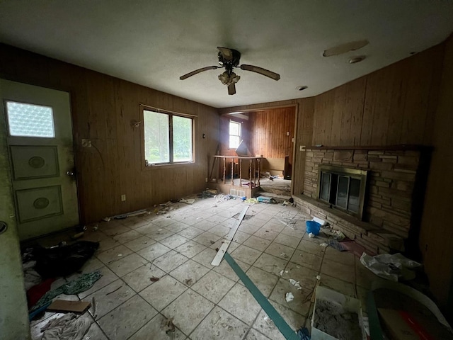 103 W 2nd St, Broadlands, IL 61816 - living room featuring wood walls, a stone fireplace, a ceiling fan, and light tile patterned floors