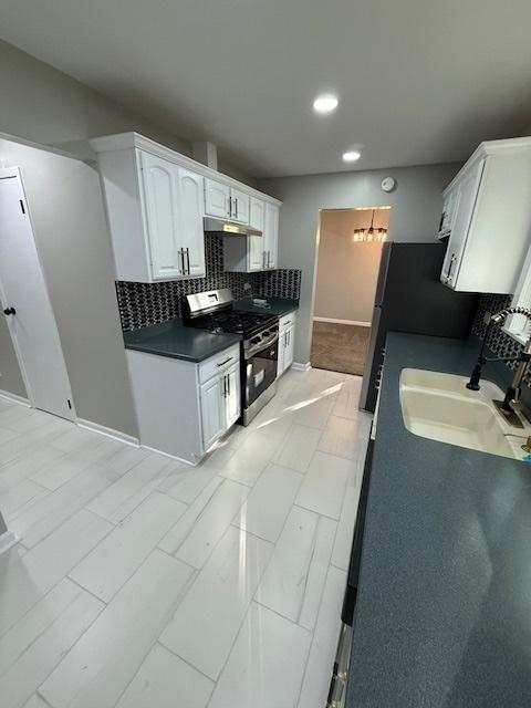 2030 University Dr, Naperville, IL 60565 - kitchen featuring stainless steel range with gas stovetop, a sink, tasteful backsplash, under cabinet range hood, and baseboards