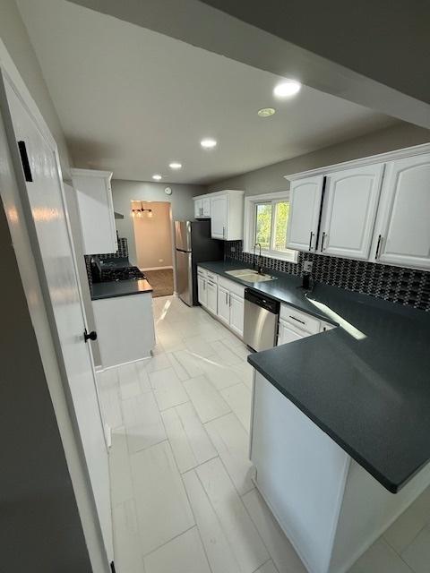 2030 University Dr, Naperville, IL 60565 - kitchen featuring stainless steel appliances, dark countertops, a sink, white cabinetry, and recessed lighting