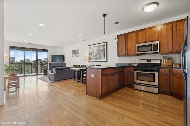 1618 S Halsted St Unit 4D, Chicago, IL 60608 - kitchen featuring stainless steel appliances, a peninsula, open floor plan, dark countertops, and light wood-type flooring