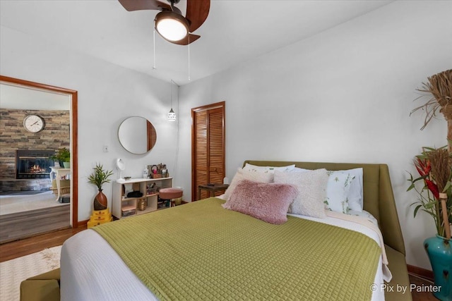 111 W N St, Plano, IL 60545 - bedroom featuring a closet, wood finished floors, a fireplace, a ceiling fan, and baseboards