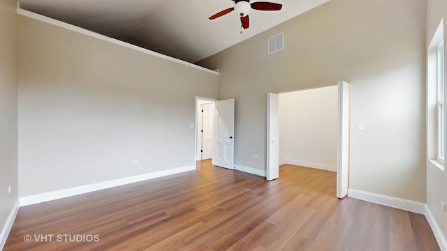 554 E Jackson St, Joliet, IL 60432 - unfurnished bedroom featuring wood finished floors, high vaulted ceiling, baseboards, and a ceiling fan