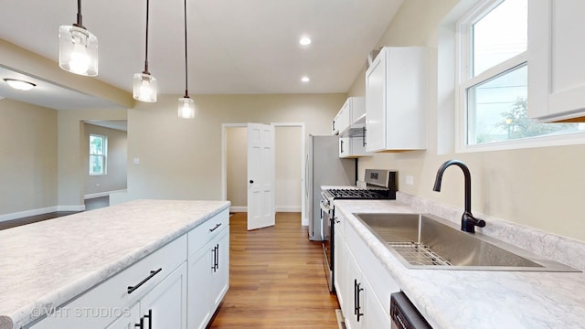 554 E Jackson St, Joliet, IL 60432 - kitchen with stainless steel gas range oven, a sink, hanging light fixtures, white cabinetry, and light wood-style flooring