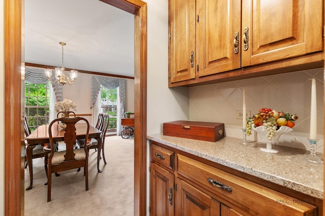 2872 Whispering Oaks Ct, Buffalo Grove, IL 60089 - kitchen featuring light colored carpet, brown cabinets, light stone counters, a chandelier, and backsplash