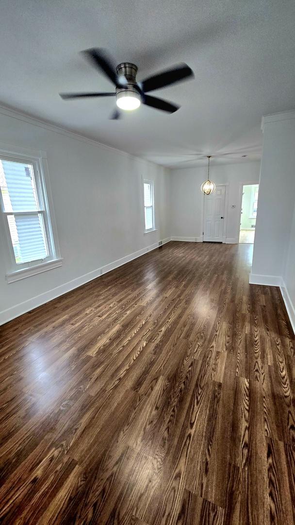 spare room with dark wood-type flooring, ornamental molding, baseboards, a ceiling fan, and a textured ceiling