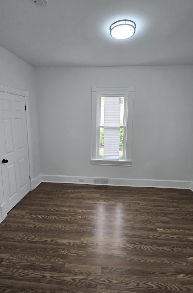 unfurnished room featuring baseboards and dark wood-style flooring