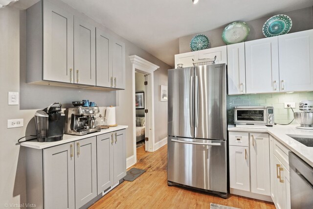 217 Circle Ave, Forest Park, IL 60130 - kitchen featuring stainless steel appliances, light countertops, light wood-style floors, backsplash, and baseboards