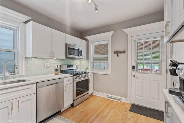 217 Circle Ave, Forest Park, IL 60130 - kitchen featuring stainless steel appliances, a sink, light wood-type flooring, light countertops, and backsplash