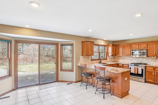 679 Gibbons Dr, New Lenox, IL 60451 - kitchen with stainless steel appliances, a peninsula, baseboards, tasteful backsplash, and brown cabinets