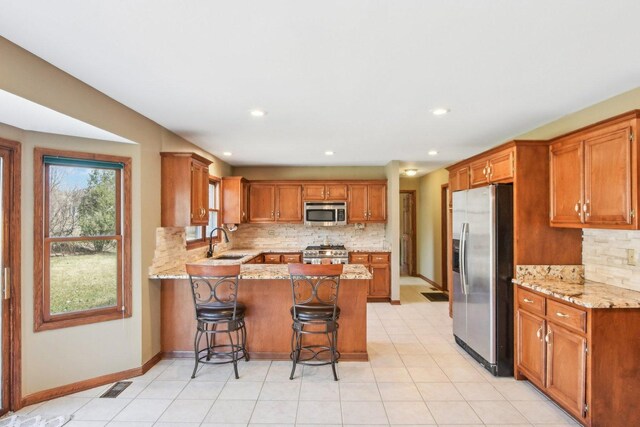 679 Gibbons Dr, New Lenox, IL 60451 - kitchen with appliances with stainless steel finishes, a sink, a peninsula, decorative backsplash, and brown cabinets