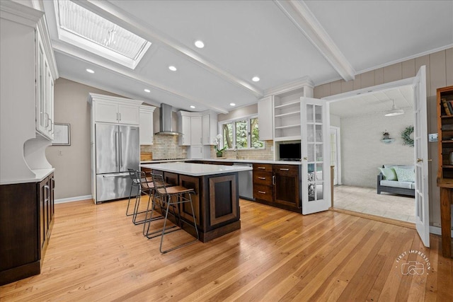 705 Meadows Rd, Geneva, IL 60134 - kitchen featuring appliances with stainless steel finishes, wall chimney range hood, a breakfast bar area, light countertops, and a kitchen island