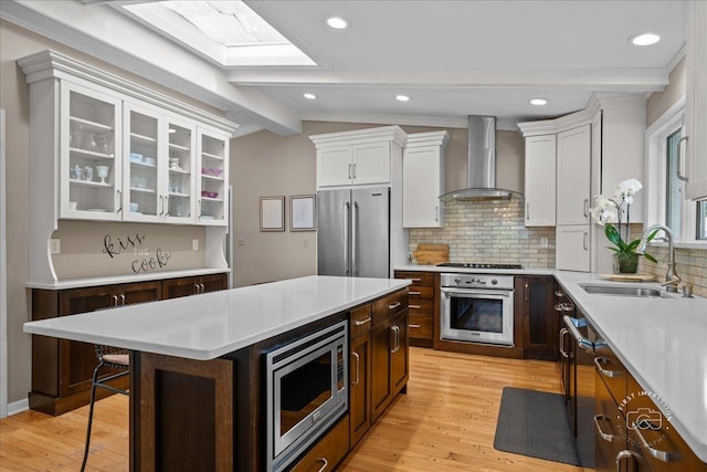 705 Meadows Rd, Geneva, IL 60134 - kitchen featuring appliances with stainless steel finishes, wall chimney exhaust hood, a sink, white cabinetry, and light countertops