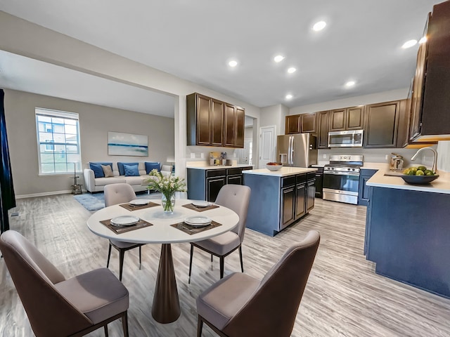 8506 Stillwater Rd, Wonder Lake, IL 60097 - kitchen with appliances with stainless steel finishes, a sink, light countertops, light wood-style floors, and a center island
