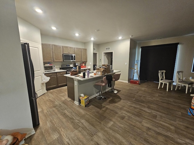 6321 Aspen Ln, Wonder Lake, IL 60097 - kitchen with appliances with stainless steel finishes, recessed lighting, dark wood finished floors, a kitchen island with sink, and a breakfast bar