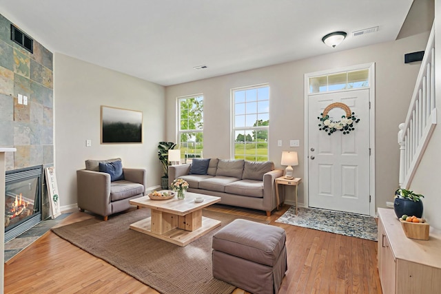 101 E Robinson Ave, Cortland, IL 60112 - living room featuring light wood finished floors, a tiled fireplace, baseboards, and stairs