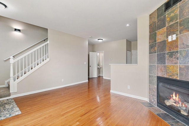 101 E Robinson Ave, Cortland, IL 60112 - unfurnished living room featuring stairs, hardwood / wood-style flooring, baseboards, a tiled fireplace, and recessed lighting