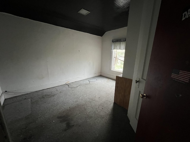 spare room with baseboards and lofted ceiling
