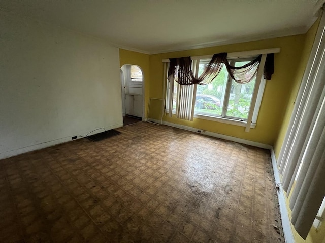 spare room with arched walkways and baseboards