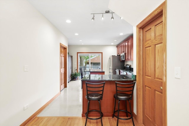 7050 26th Pkwy, Berwyn, IL 60402 - kitchen with appliances with stainless steel finishes, dark countertops, a peninsula, a kitchen bar, and baseboards