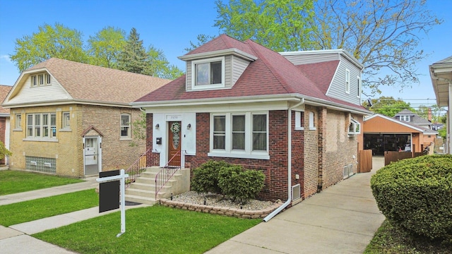 7050 26th Pkwy, Berwyn, IL 60402 - view of front of house featuring brick siding, a front yard, a shingled roof, an outbuilding, and a detached garage