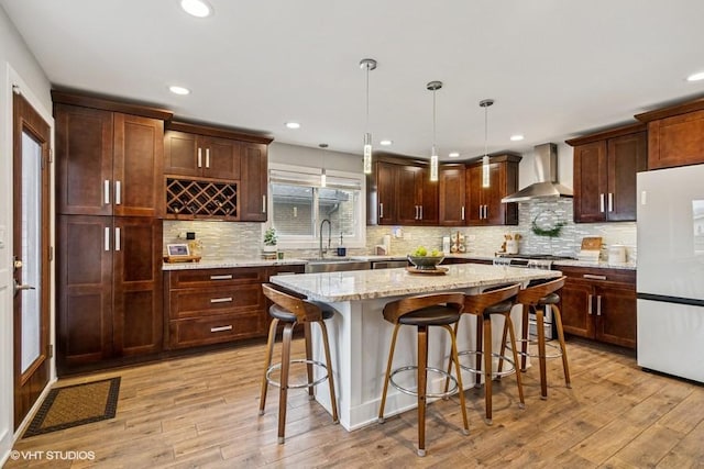 7146 S Oketo Ave, Bridgeview, IL 60455 - kitchen featuring freestanding refrigerator, wall chimney exhaust hood, a sink, a center island, and a kitchen breakfast bar