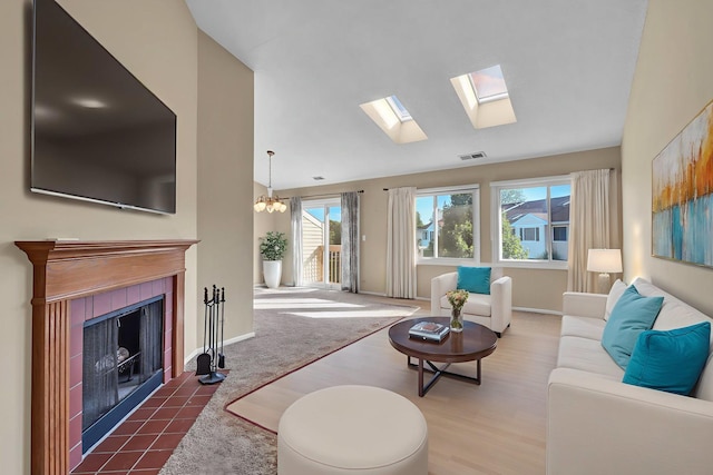 143 W Fabish Dr Unit 143, Buffalo Grove, IL 60089 - living room with a tiled fireplace, vaulted ceiling, wood finished floors, a skylight, and a chandelier