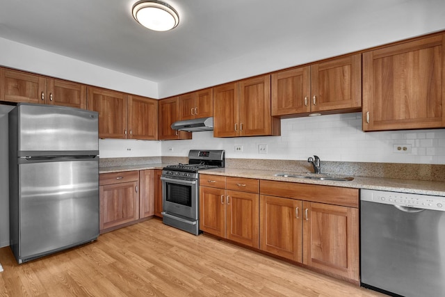 143 W Fabish Dr Unit 143, Buffalo Grove, IL 60089 - kitchen featuring appliances with stainless steel finishes, under cabinet range hood, brown cabinets, light wood-style flooring, and light stone countertops