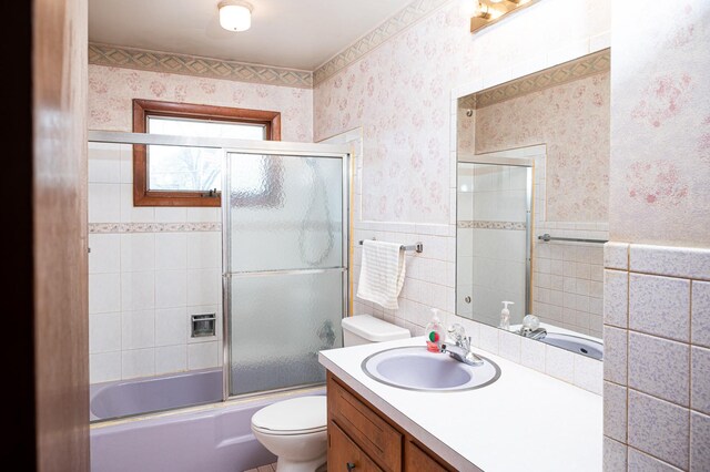 207 Muehl Dr, Lockport, IL 60441 - bathroom with wallpapered walls, toilet, vanity, shower / bath combination with glass door, and tile walls