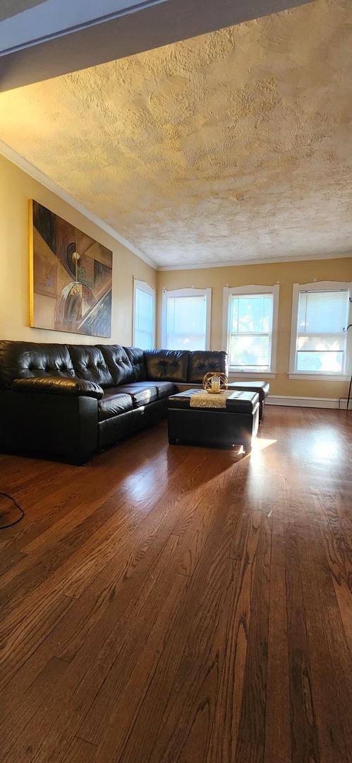 1605 S 16th Ave, Maywood, IL 60153 - living room featuring wood finished floors, a textured ceiling, healthy amount of natural light, and crown molding