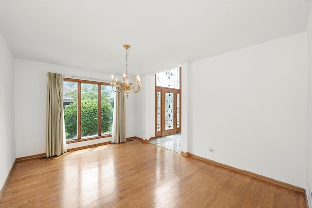 empty room with a chandelier and light wood finished floors
