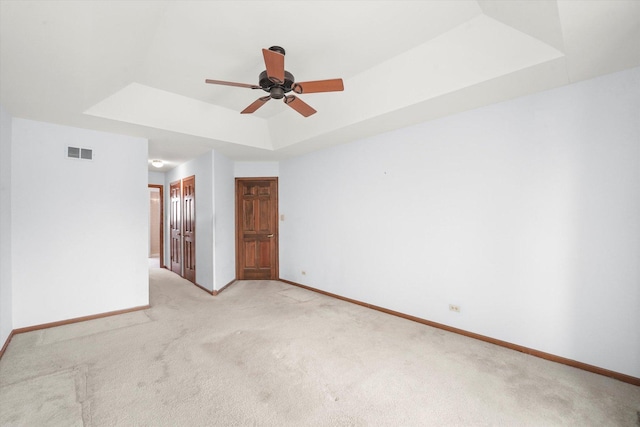 unfurnished room featuring a tray ceiling, carpet floors, and ceiling fan