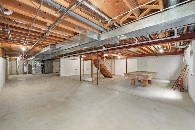 unfinished basement with heating unit, stairway, billiards table, and water heater