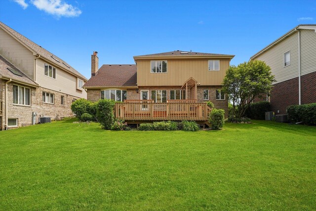 back of property featuring brick siding, a deck, a lawn, and a chimney
