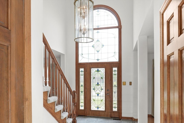 foyer entrance with a high ceiling, a chandelier, and stairs