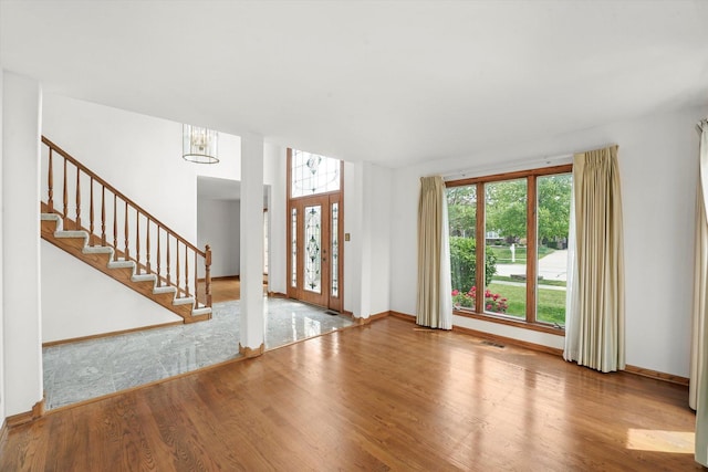 entrance foyer featuring wood finished floors, a chandelier, and stairs