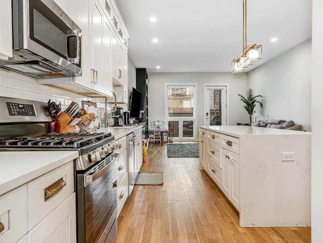 1707 S Jefferson St Unit 1, Chicago, IL 60616 - kitchen with appliances with stainless steel finishes, light countertops, light wood-style floors, white cabinetry, and pendant lighting
