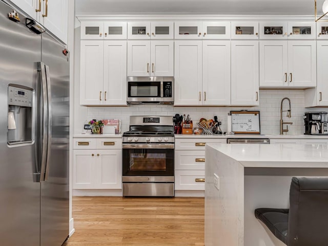 1707 S Jefferson St Unit 1, Chicago, IL 60616 - kitchen with stainless steel appliances, light countertops, light wood-style flooring, white cabinetry, and backsplash