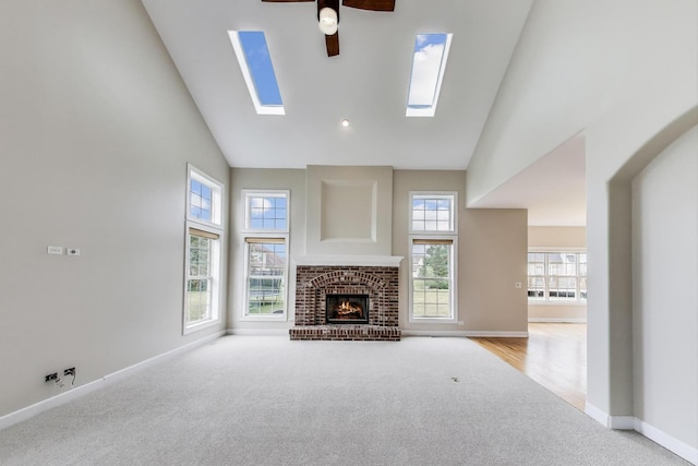 12354 S Blue Water Pkwy, Plainfield, IL 60585 - unfurnished living room with high vaulted ceiling, carpet flooring, ceiling fan, a skylight, and a fireplace