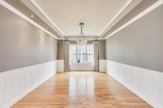 12354 S Blue Water Pkwy, Plainfield, IL 60585 - spare room with a chandelier, a raised ceiling, wainscoting, crown molding, and light wood-type flooring