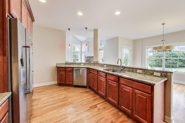 12354 S Blue Water Pkwy, Plainfield, IL 60585 - kitchen featuring appliances with stainless steel finishes, light wood-type flooring, decorative light fixtures, a peninsula, and light stone countertops