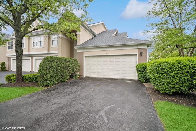 3047 Lexington Ln, Glenview, IL 60026 - view of front facade with driveway, stucco siding, a garage, and roof with shingles